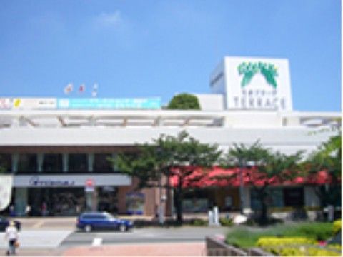 百貨店の外観である。大型ショッピングモールとは道路を挟んで並んでいる。横に広い建物で白を基調にした外観になっている。