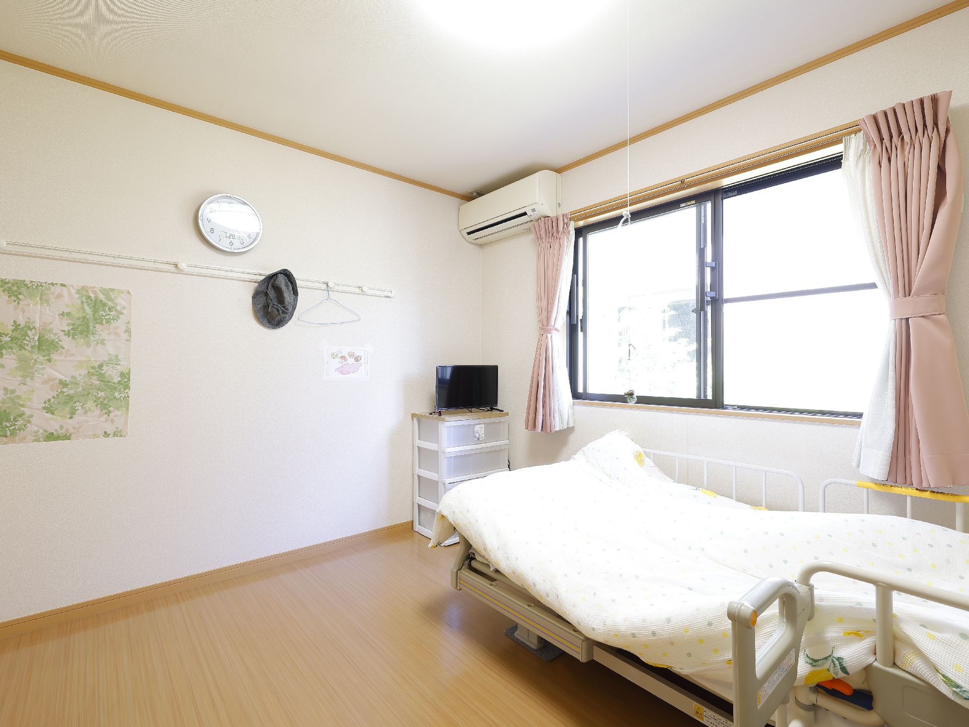 大きな窓が設置され、介護ベッドや収納が置かれている居室