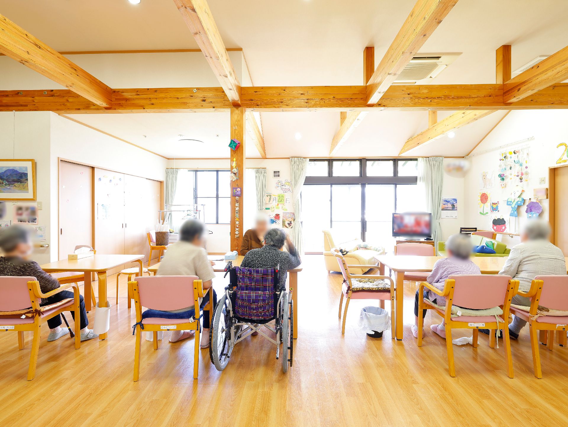 複数のテーブルが設置され、入居者が楽しく会話をしているリビング