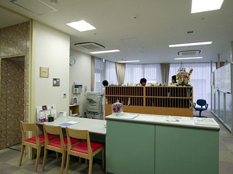 カウンターの隣には一段低いテーブルと赤い椅子が３脚置かれている。外側から事務所の様子を見ることができる。