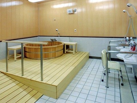 浴室には檜の風呂桶と数台のシャワーが設置されている。要所にスロープや手すりが設けられ椅子も用意されている。