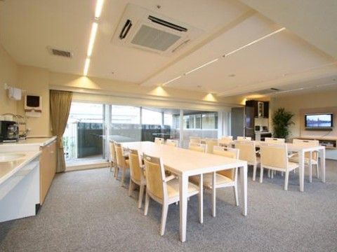 壁にテレビが設置され、その横に背の高い観葉植物が置かれている食堂