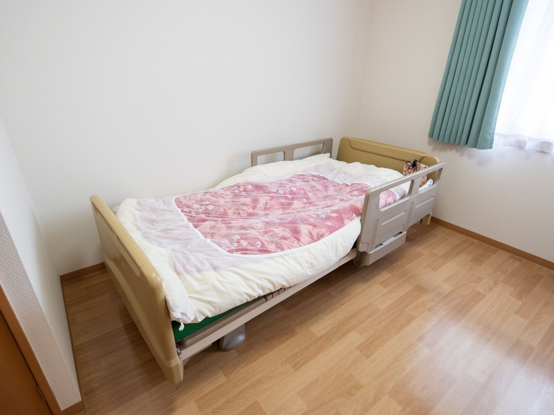 居室に備え付けのベッドである。布団などの寝具が落ちてしまうことのないよう配慮され、抑えが取り付けられている。