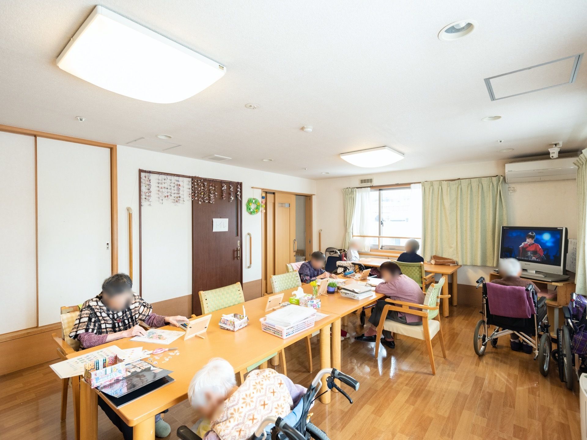 壁には、折り紙などで手作りされた作品が飾られている。大きなテーブルにたくさんの椅子が用意され、好きな場所に座ることができる。