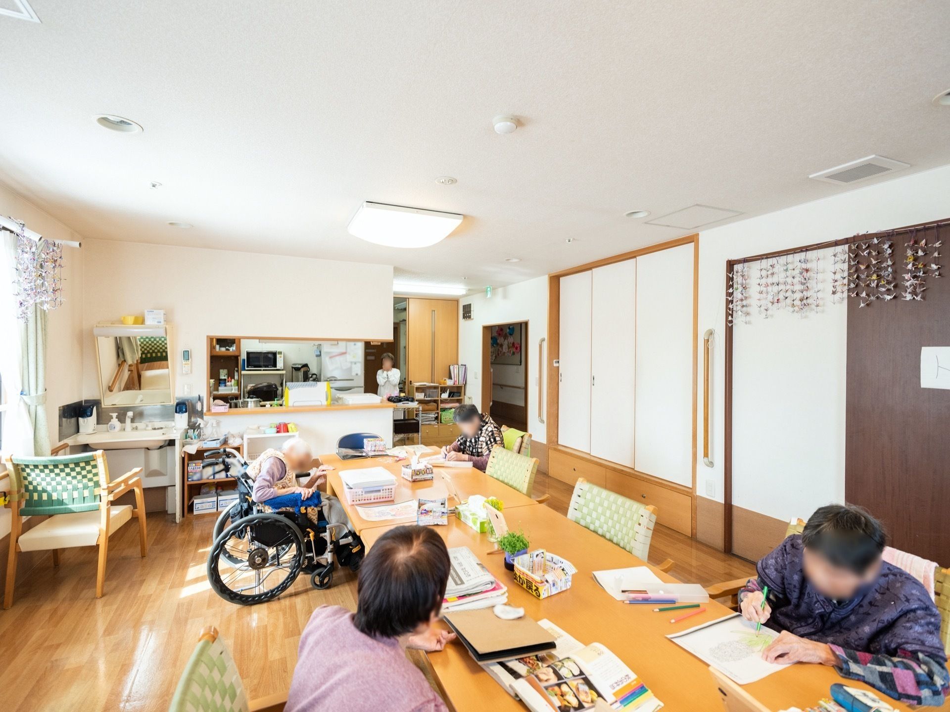 大きなテーブルにあるリビングで塗り絵のレクリエーションをする高齢者