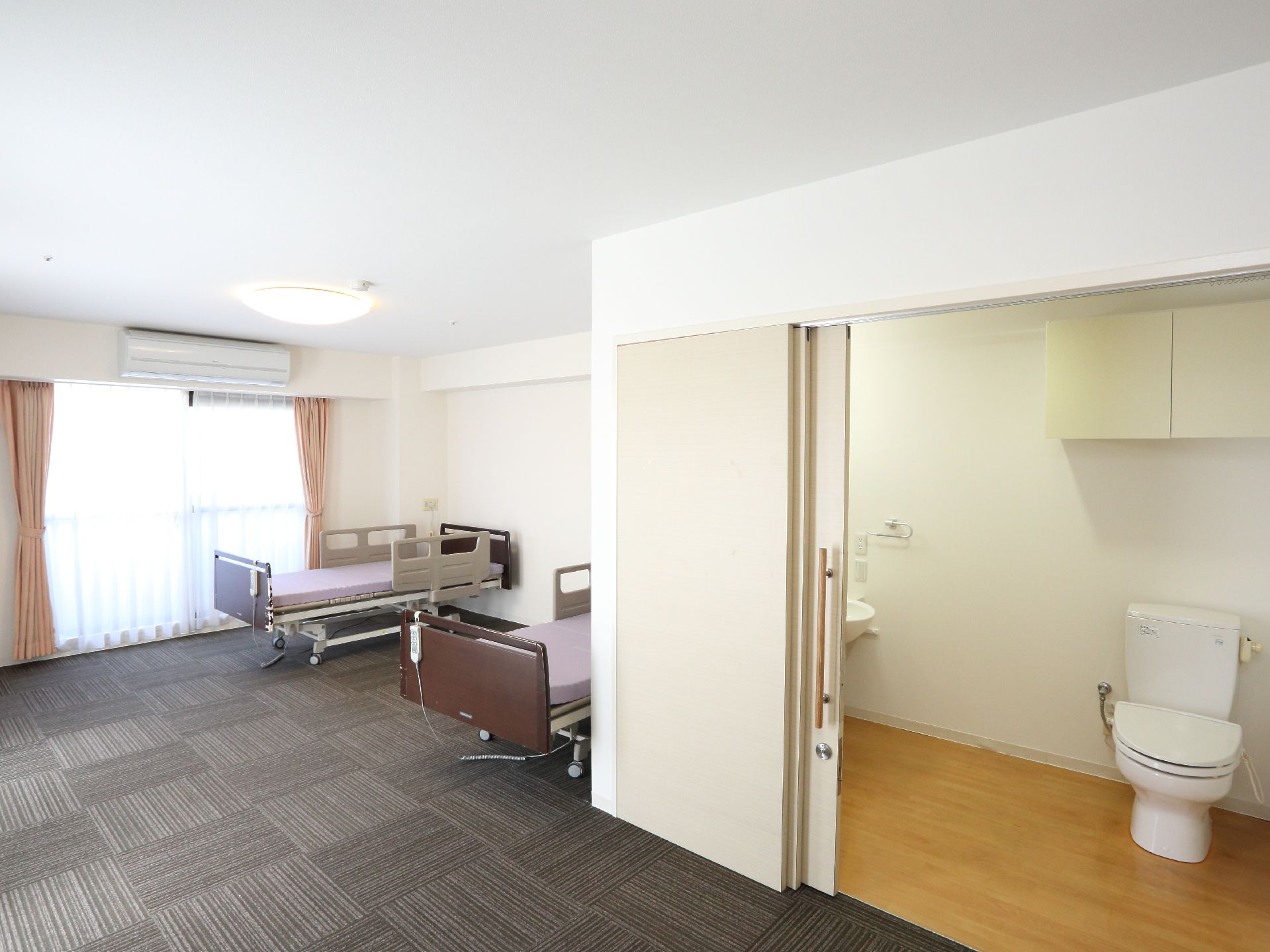 居室内には、大きな引き戸式の安全に開閉できる扉がある。中にトイレや洗面台があり、広々としたスペースになっている。
