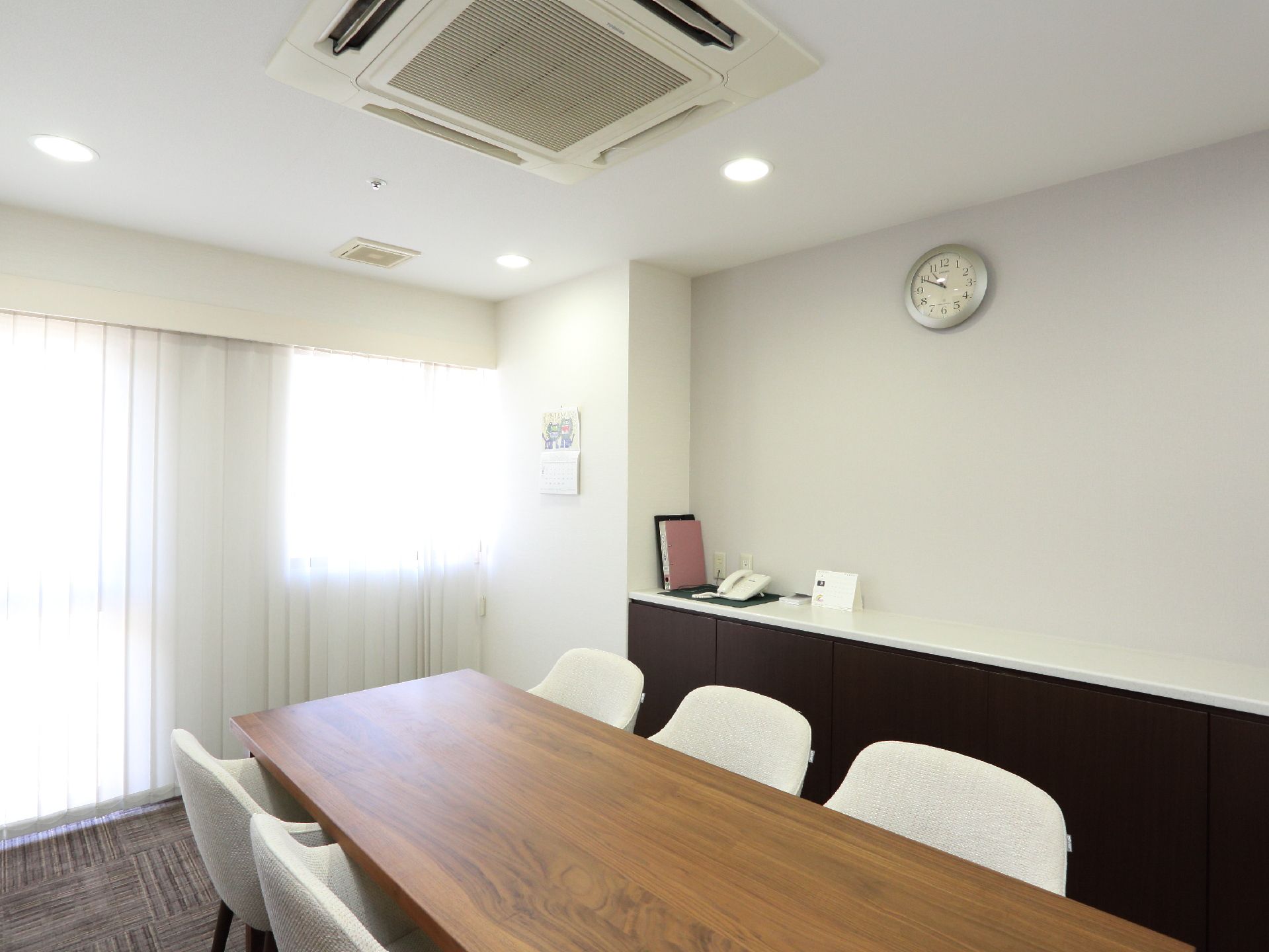 ゆっくり会話を楽しむことができる空間で、外からの光が入り明るい。白い壁に木目のテーブルが設置され、落ちつく雰囲気になっている。