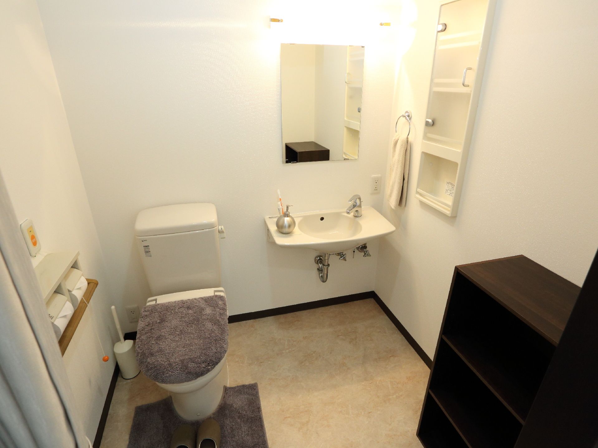 トイレの個室内に、洗面台もあり、すぐ横には棚もついているので、洗面道具やトイレに使用する道具をしまっておくことができる。