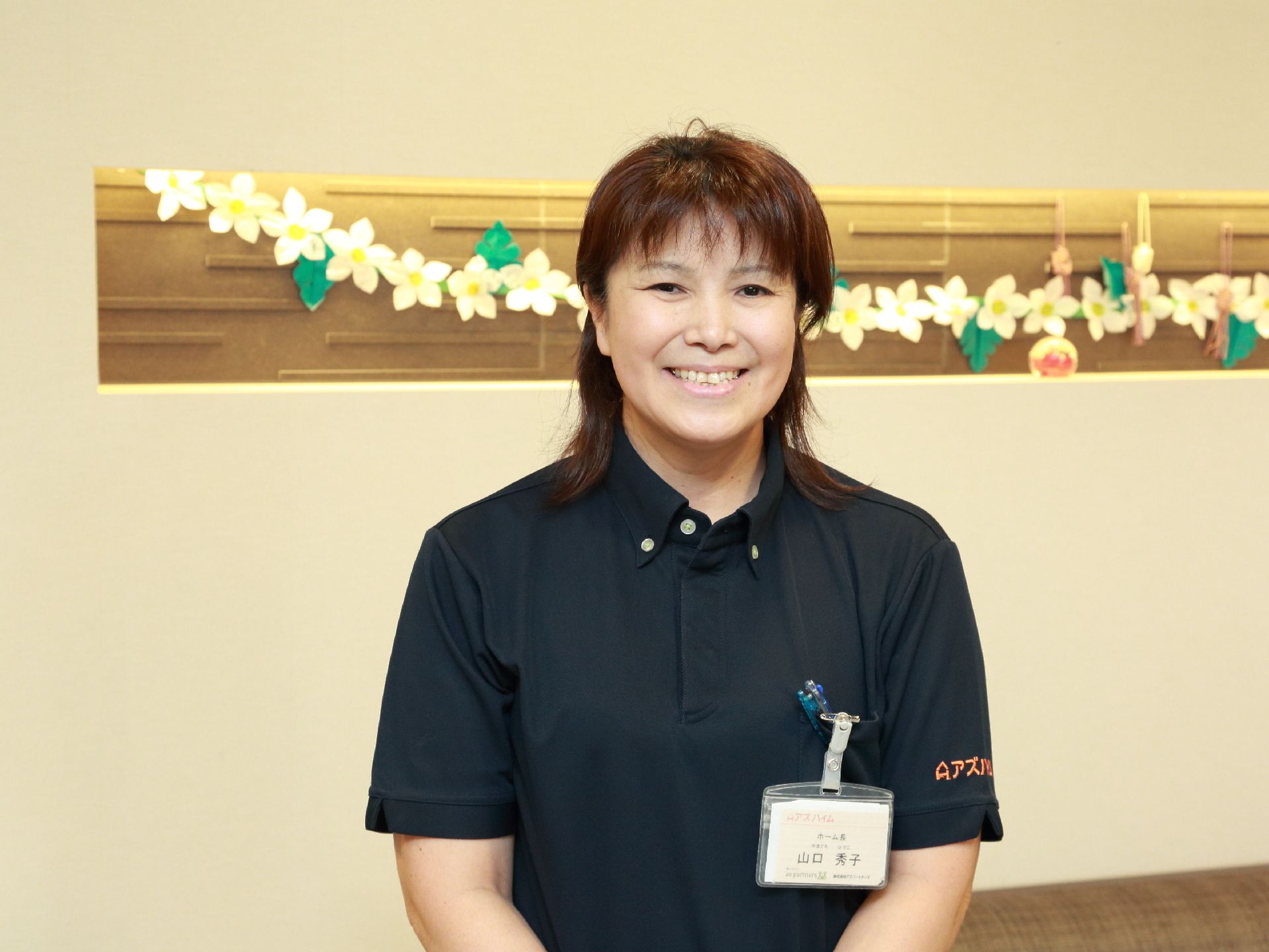 黒色のユニフォームを着てにこやかに笑っている女性スタッフ