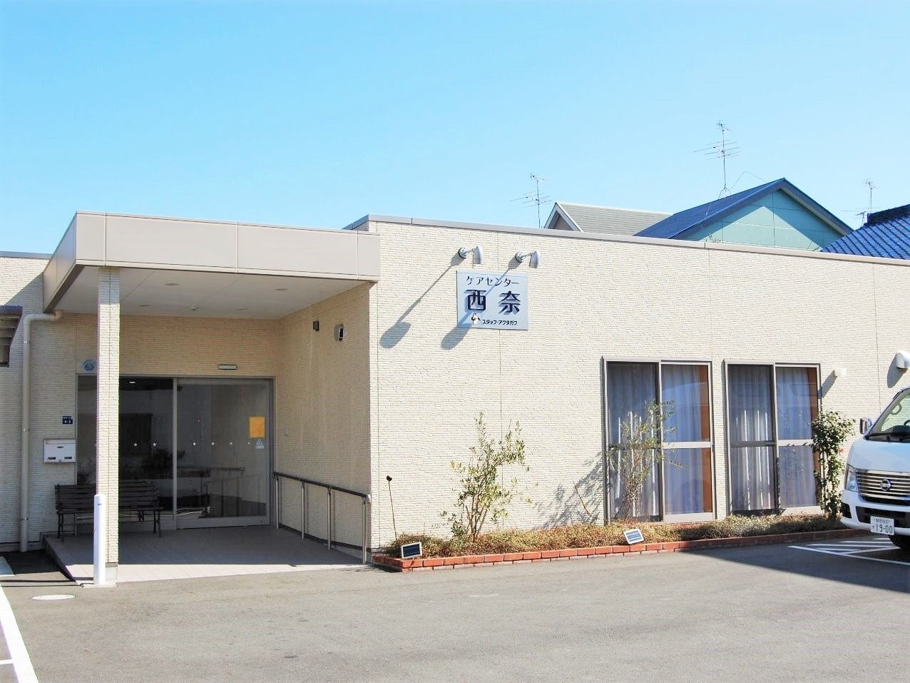 平屋建ての建物の玄関部分には屋根が付き、外壁にはホームの名前が書かれている。
