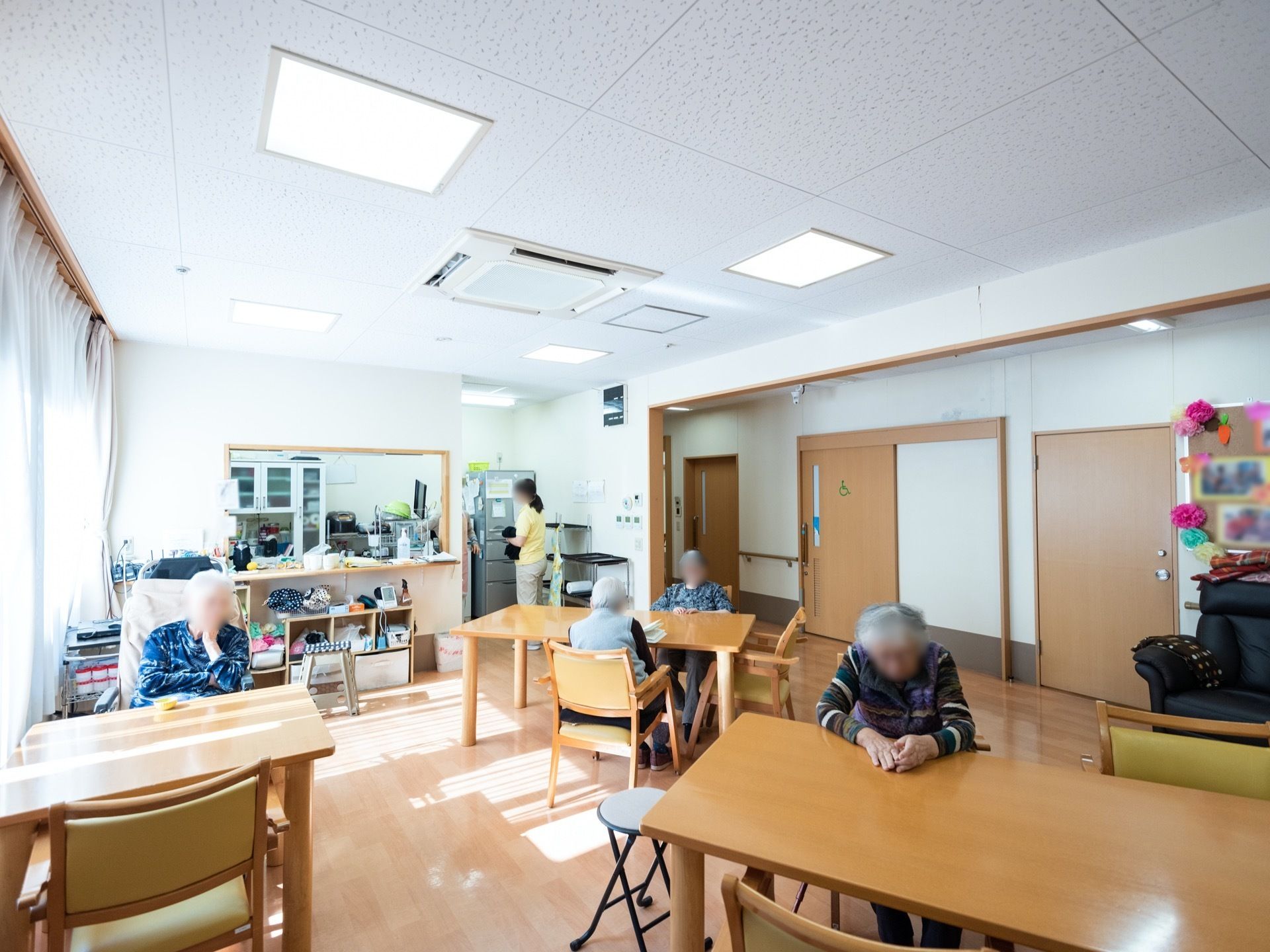 キッチンが併設された食堂である。キッチンには冷蔵庫、調理家電が備わっている。入居者様が集まり、思い思いに過ごしている。