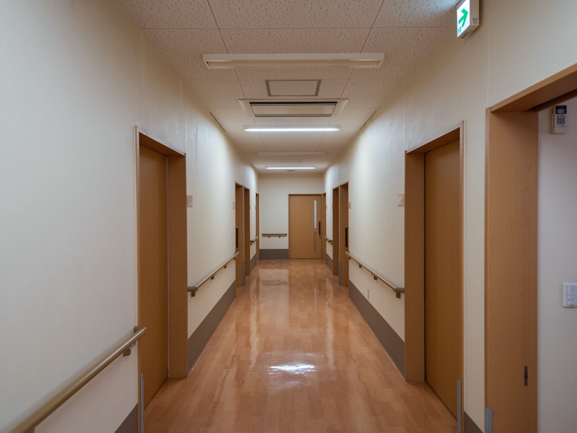 個室に繋がる通路である。部屋の扉はベージュ調に施されており、スライドドアである。壁には手すりががある。