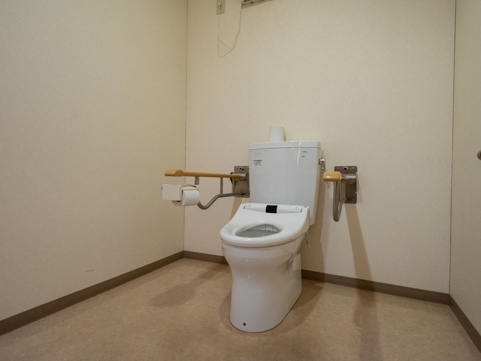 広々とした洋式のトイレである。アームレストが設置されており、トイレットペーパーががある。