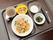 食事がトレーにのせられて用意されている。この日のメイン料理は、海鮮焼きそばである。小鉢やデザートもある。