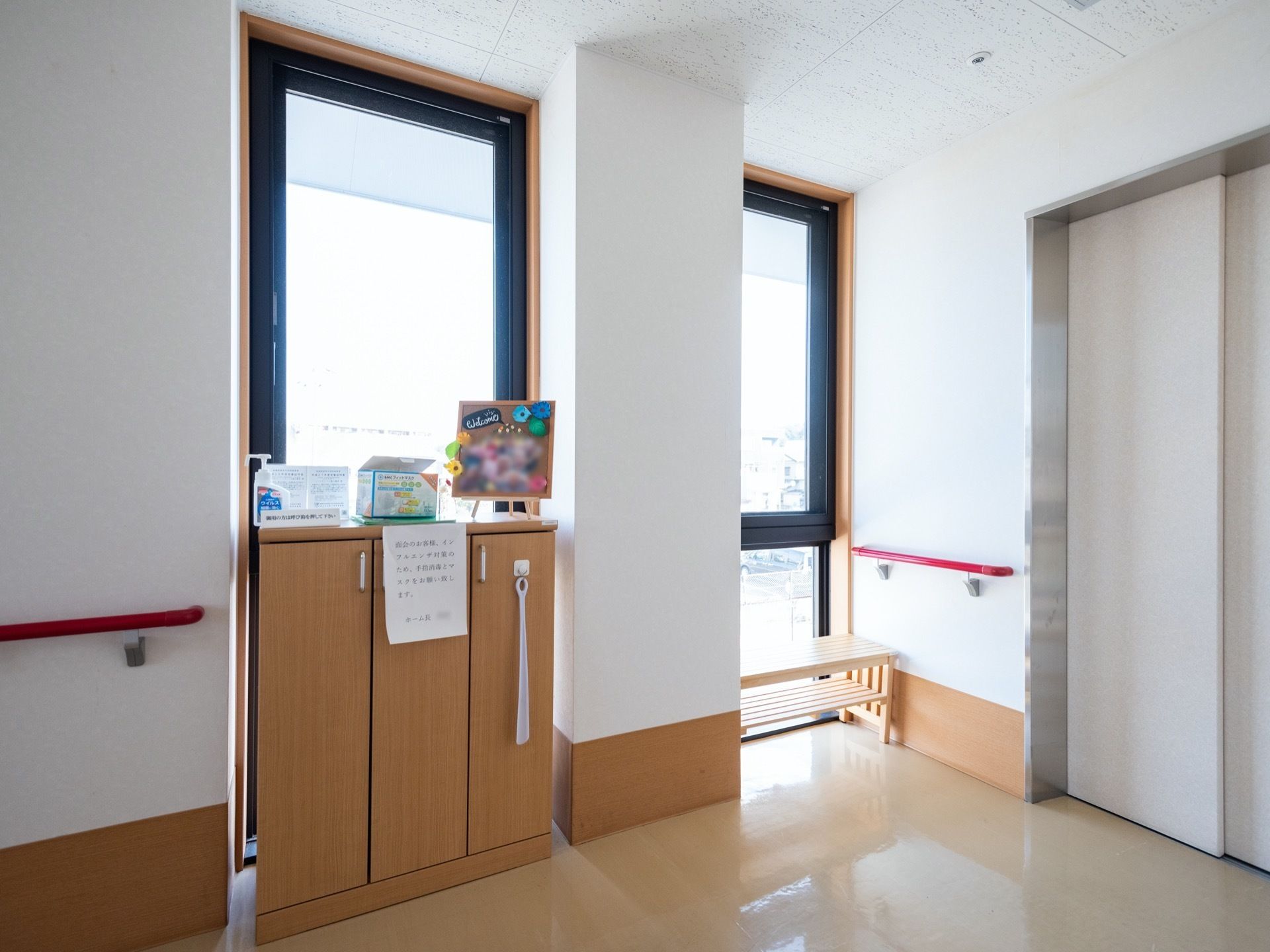 エレベーターが1基設置されている。窓からは自然光が差し込んでいる。壁には手すりががある。