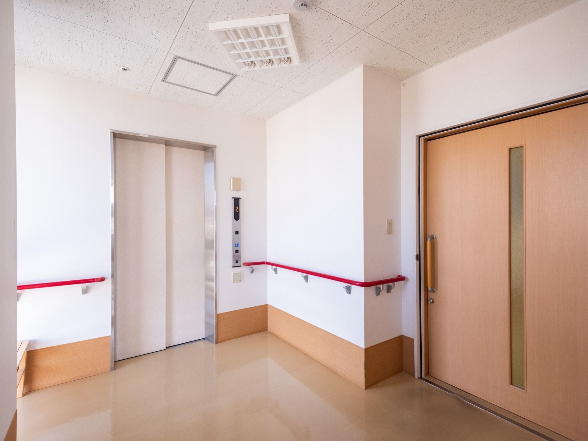 白い扉のエレベーターが1基設置されている。壁には色鮮やかな手すりががある。部屋の扉はスライド式である。