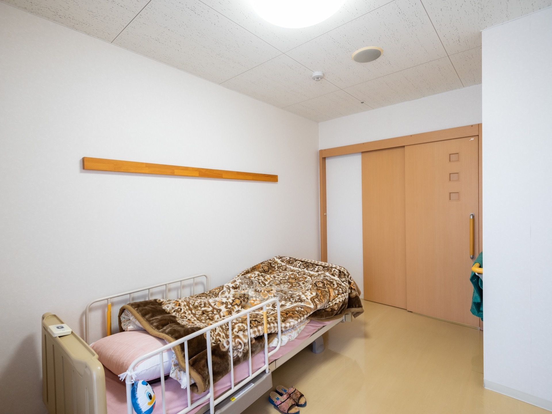 個室の部屋にベッドが設置されており、寝具が用意されている。床にはスリッパがあり、掃除がしやすいようにフローリングである。