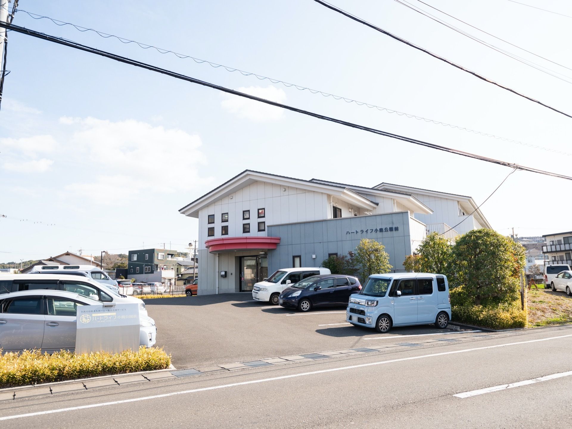 シックな雰囲気の施設外観である。2階建ての建物になっている。敷地内には駐車スペースが設けられており、車が停められている。