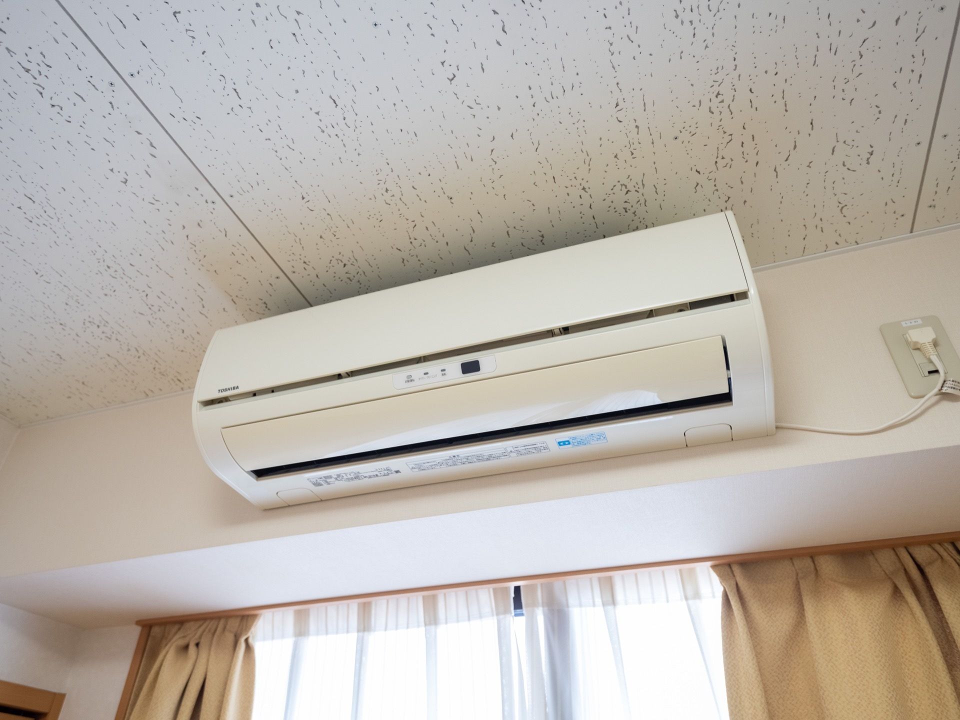 個室の部屋には窓が設置されており、ベージュのカーテンが掛けられている。エアコンが取り付けられている。