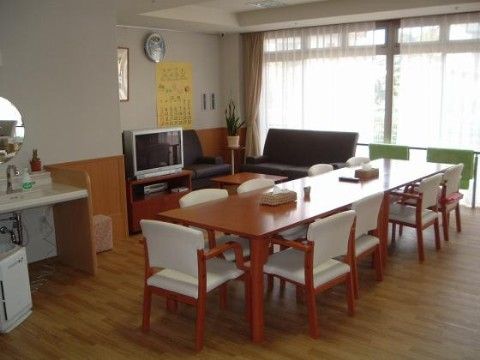 壁のうち一面がガラスになっている部屋で、そこに沿うように黒い革のソファや緑の椅子などが置かれている。