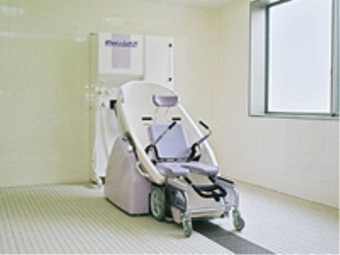 白いタイル床の浴室で、中央部分のみ黒く線が引かれたようなデザインになっている。浴槽などはなく、機械浴用の設備のみがある。