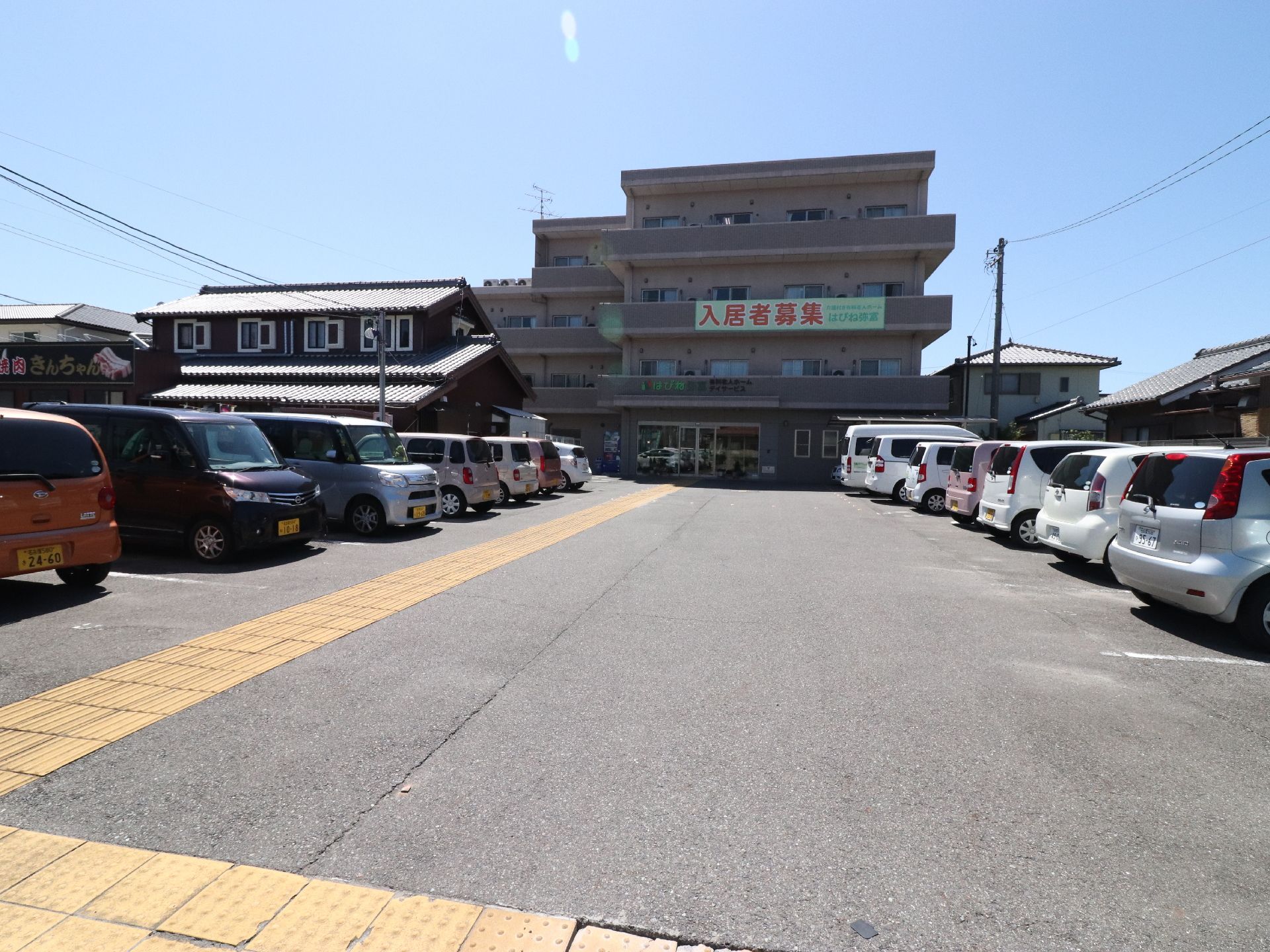 施設前は車を10台以上駐車できるスペースになっている。視覚障がい者の誘導用ブロックが入口まで続いている。