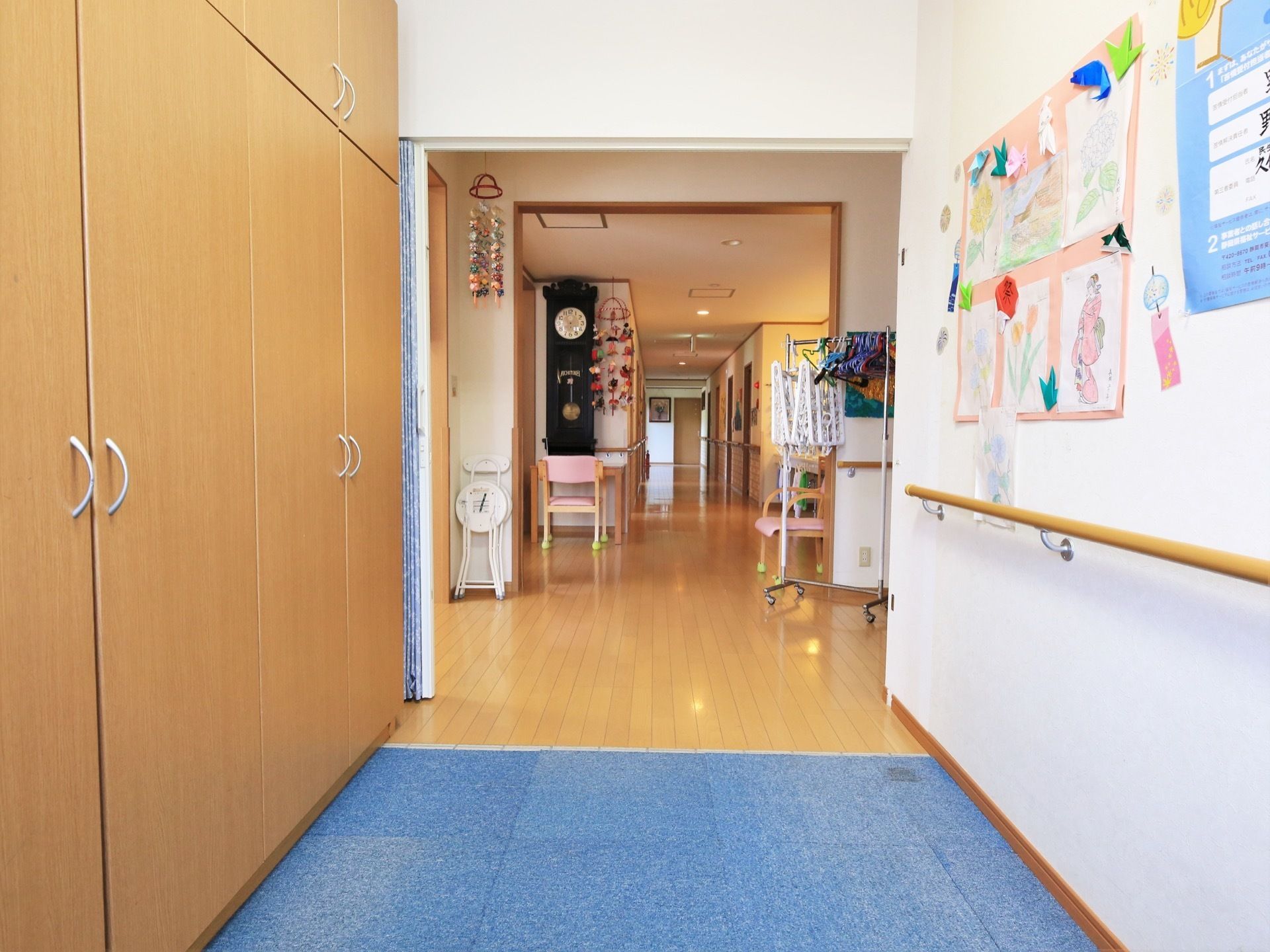 玄関を入った先にある廊下。壁には手すりが設置され、手作りの飾りつけやお知らせの紙が貼られている。