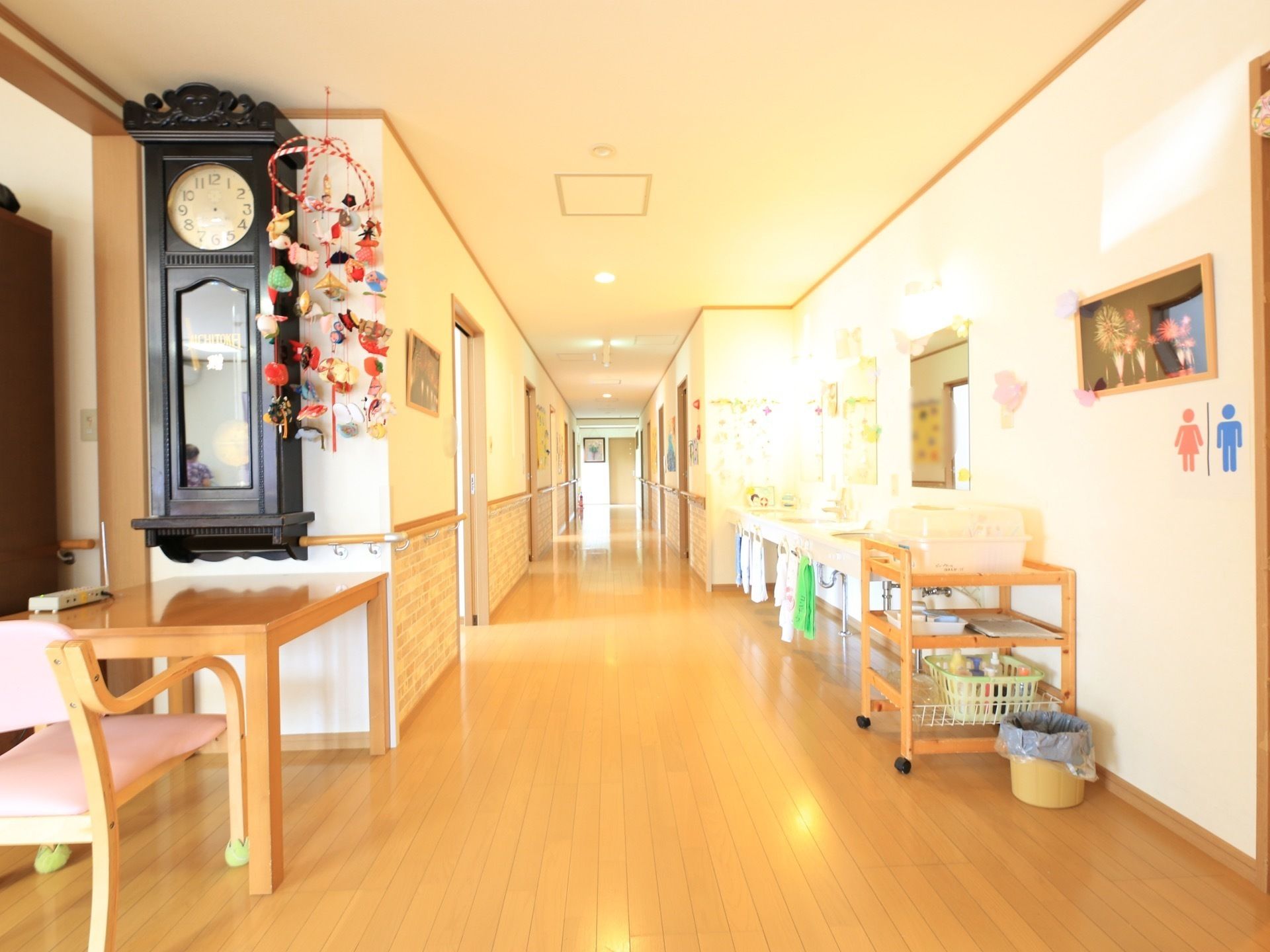 大きな古時計がかけられ、壁に季節の飾り付けをした廊下