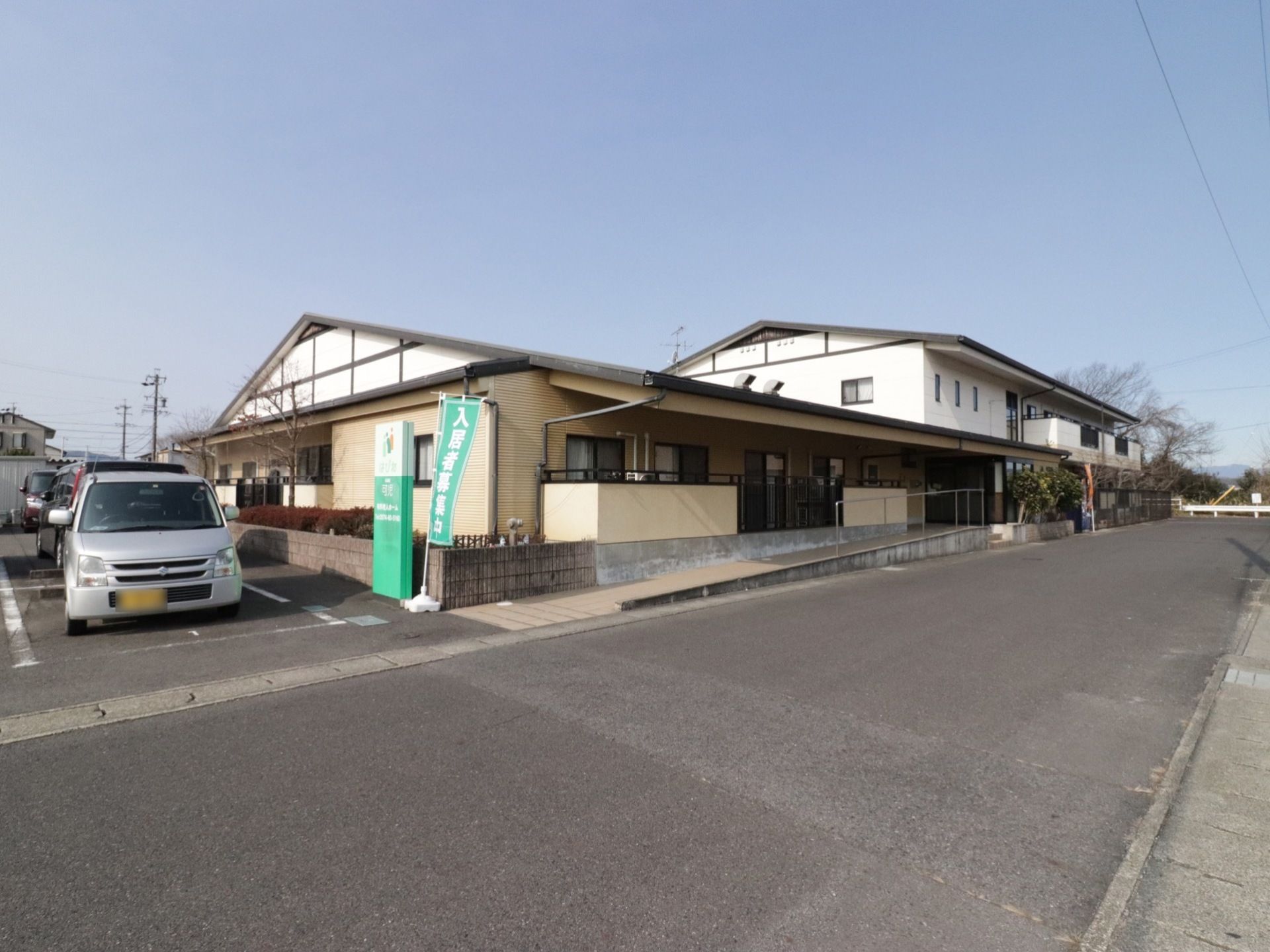 玄関の前には、緩やかなスロープが設置されている。建物の隣には、広い駐車場がある。周囲には大きな建物がない。