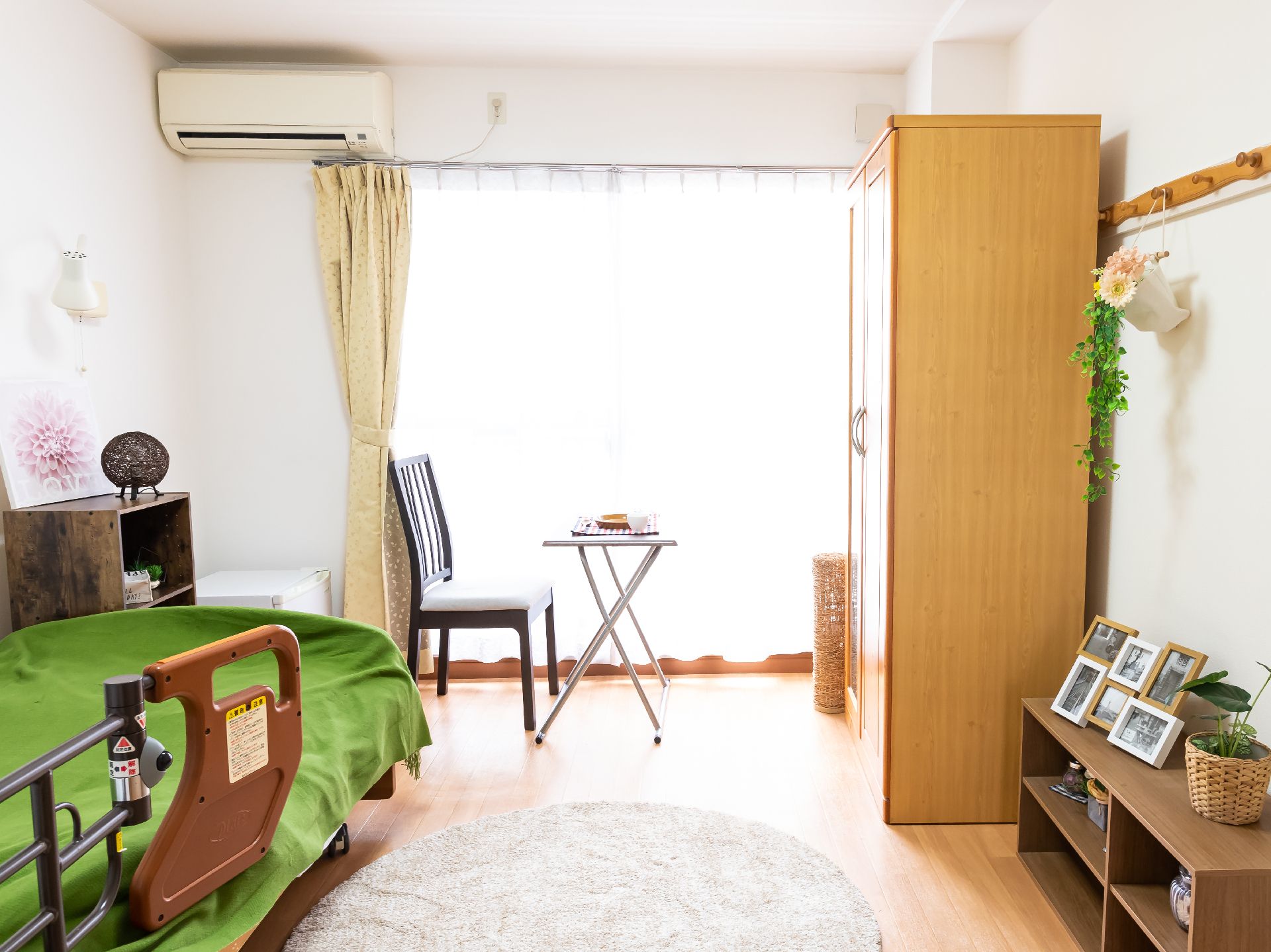 大きな窓から日差しがあたり、介護ベッドや家具を照らしている居室
