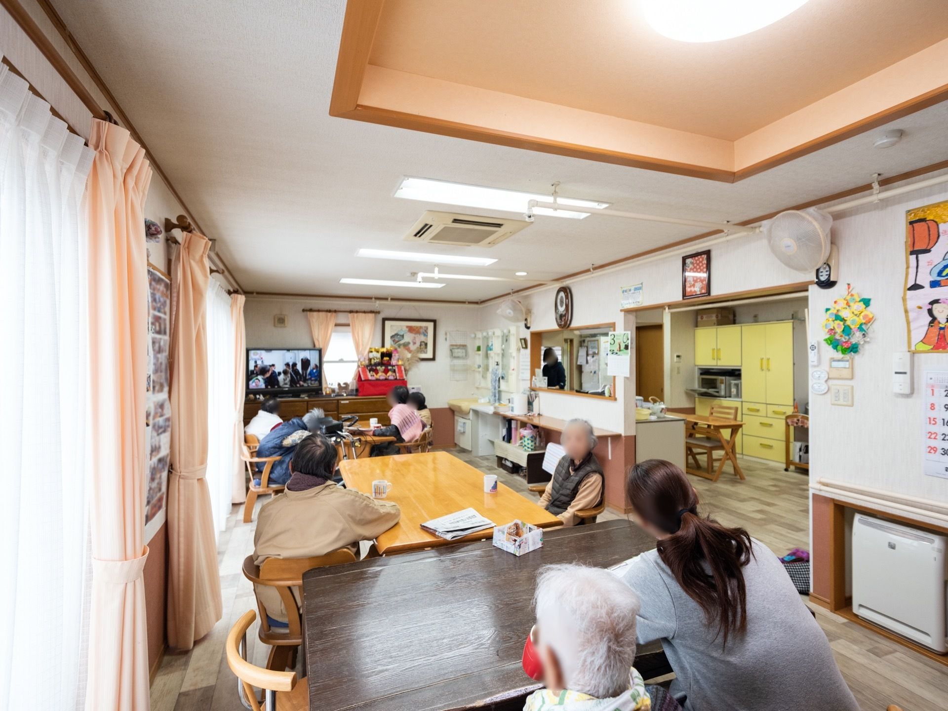 窓を多く設けた明るい食堂である。大型液晶テレビが完備されている。入居者様やスタッフが番組を観て楽しんでいる。