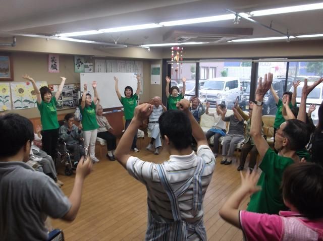 元気いっぱいに手を上に挙げて体操をしているスタッフと入居者の様子。