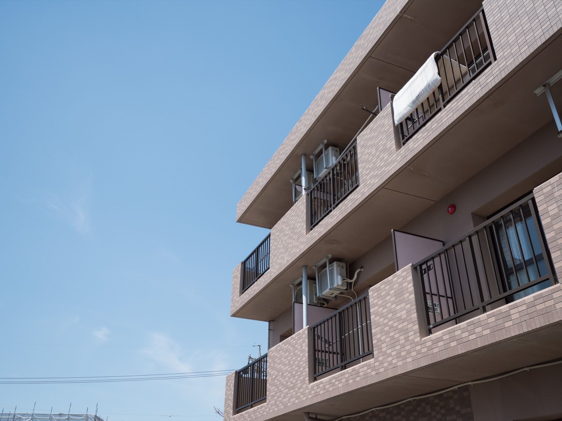 落ち着いた色合いの外壁のマンション風施設外観である。３階建てで、ベランダは一部壁を抜き、見通せるように造られている。