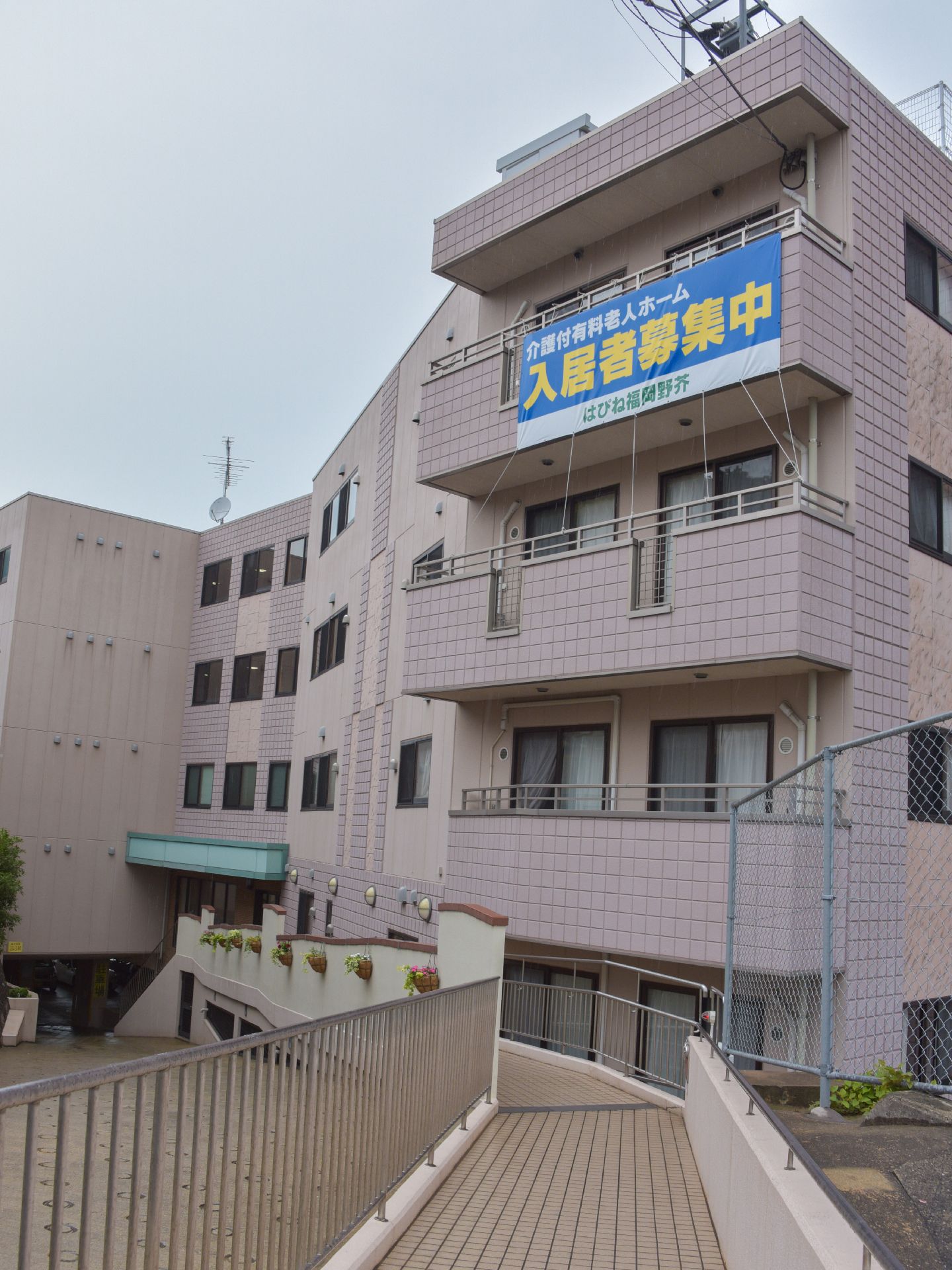 主要道路からエントランスまでは緩やかな下りのスロープがある。また、反対側には階段がありどちらからでも入ることができる。