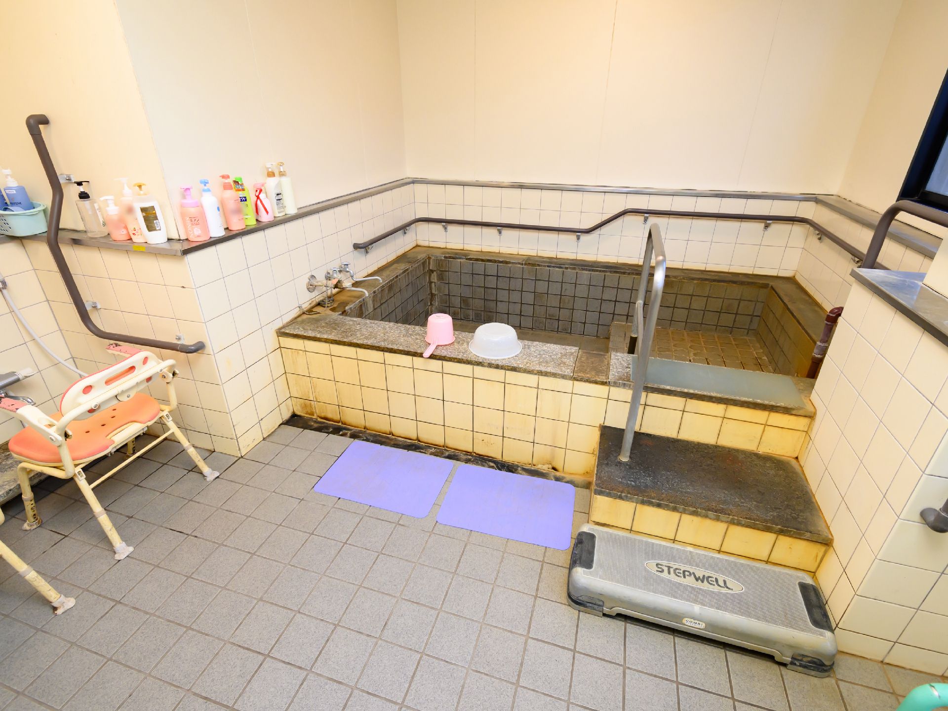 手すりが多数取り付けられた、温泉風の浴室