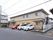 施設は横に長い２階建ての建物である。屋根付きの自転車置き場や、外階段もついている。隣りの建物との間には白いフェンスが設置されている。