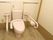 手すりが両サイドに設置された温水洗浄便座。手すりにはトイレットペーパーホルダーも付いている。