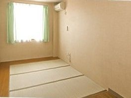畳が敷かれたフローリングの居室には大きな窓とエアコンが付いている。
