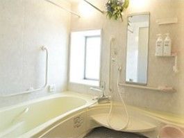 一人用の浴槽が設置された浴室。シャワーもあり、手すりが壁についている。