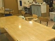 テーブルが置かれた談話室には洗面所や布で目隠しがされた棚がある。