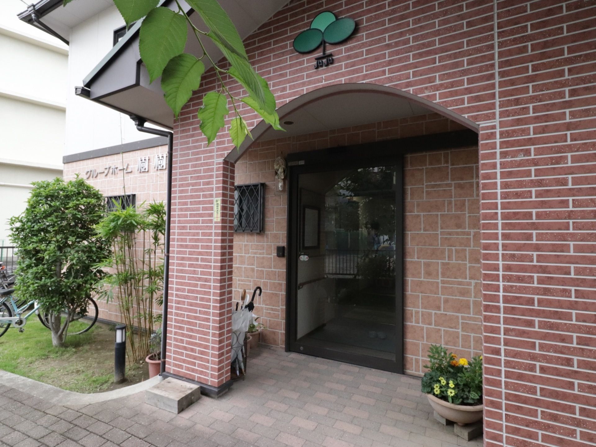 茶色の色調の落ち着いた玄関。段差がなく、大きな自動扉があり、安心して出入りできる。玄関脇の寄せ植えも美しい。