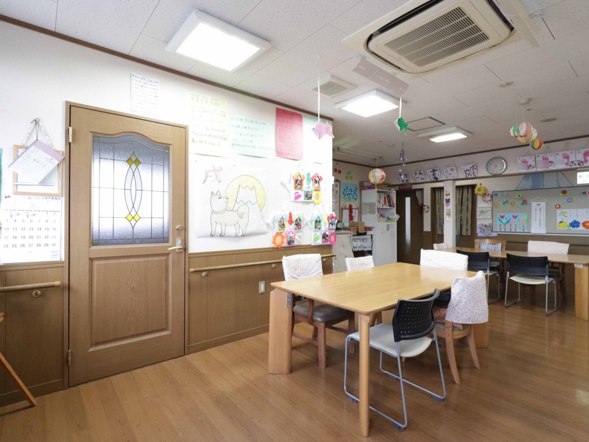 壁や天井には、入居者様やスタッフの作った作品が飾られ、明るい雰囲気の部屋である。壁には手すりがあり、移動も安心である。