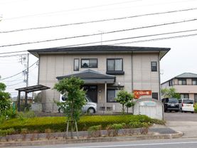 白い壁に日本風の屋根が取り付けられた民家のような施設の外観