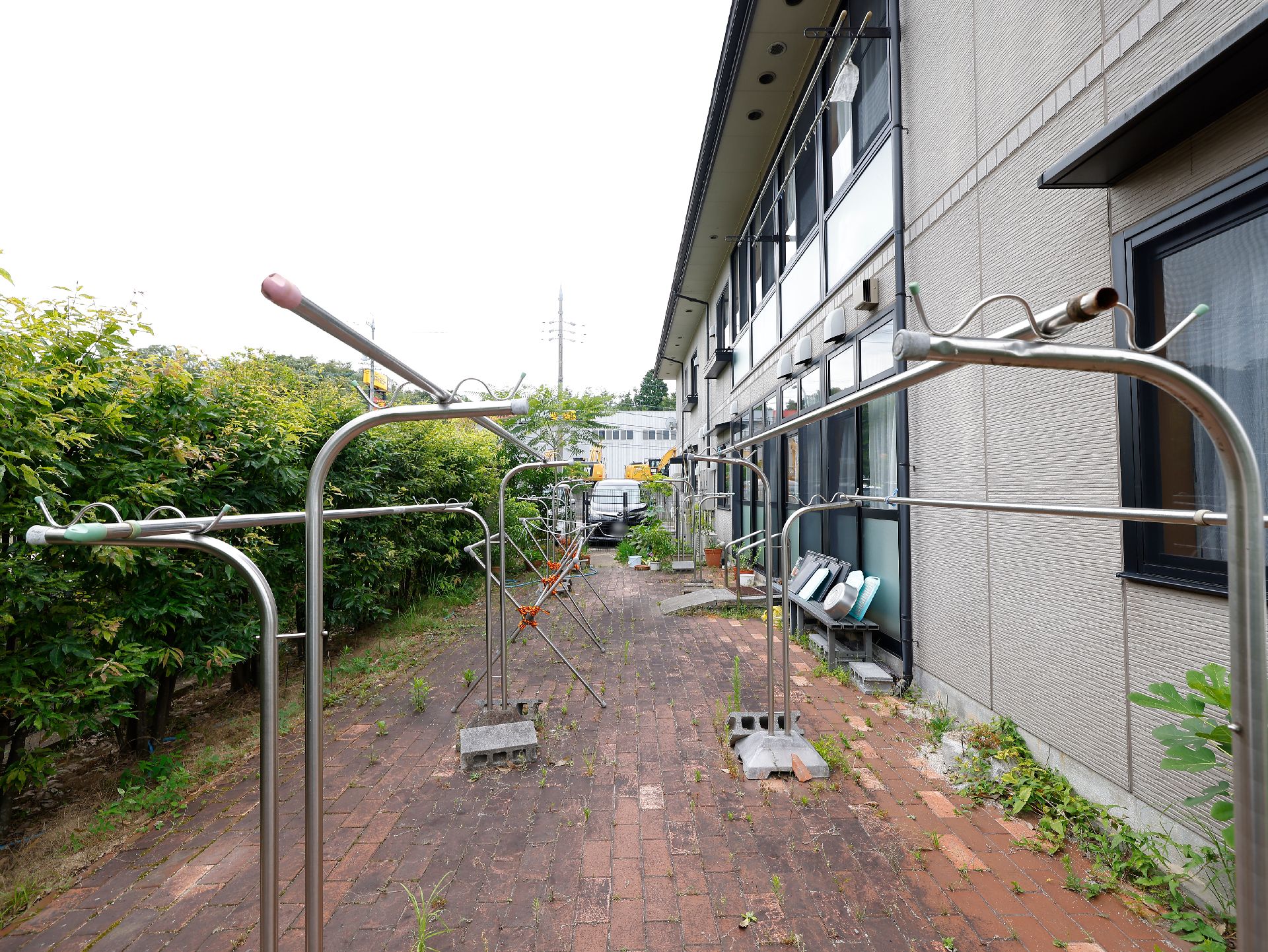 木々の垣根が作られ、物干し竿が置かれている施設の中庭