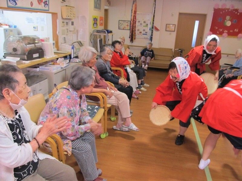 どじょうすくいの衣装をまとったスタッフがご入居者様に笑いかけている様子