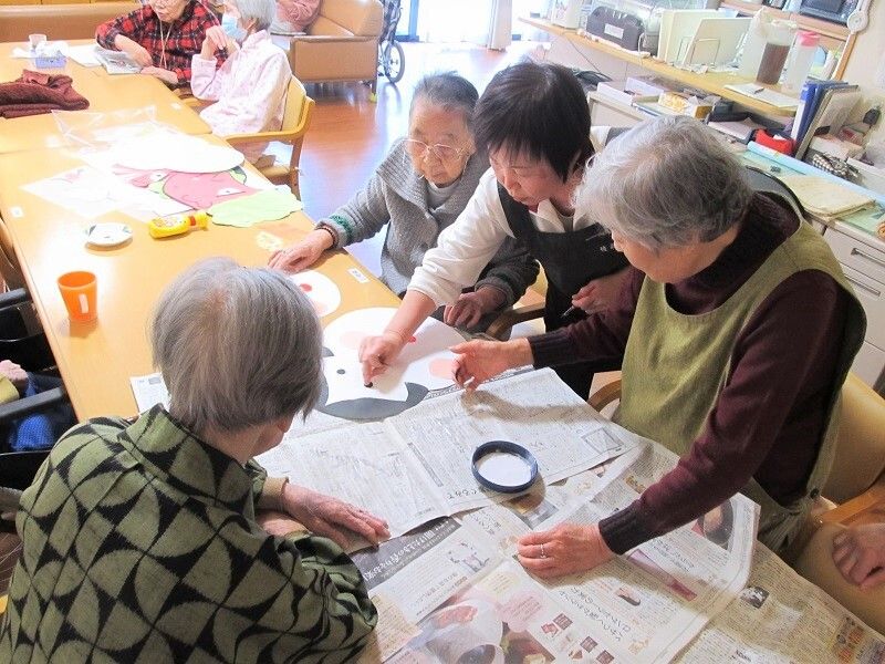 節分の掲示物を作成するご利用者と、そのサポートをする女性スタッフの様子
