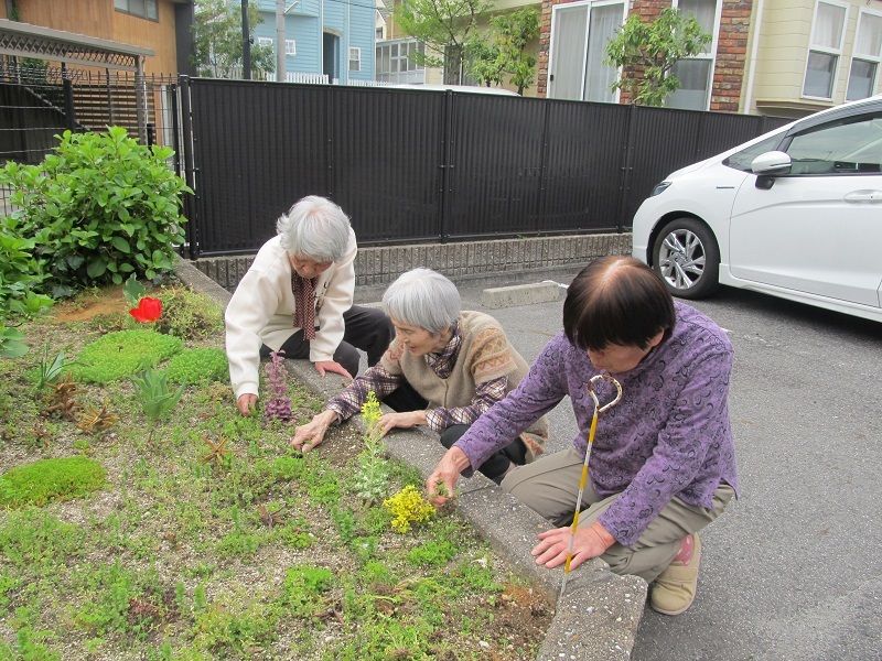 施設の駐車場にある庭の雑草を抜いたり、手入れをする女性利用者の様子