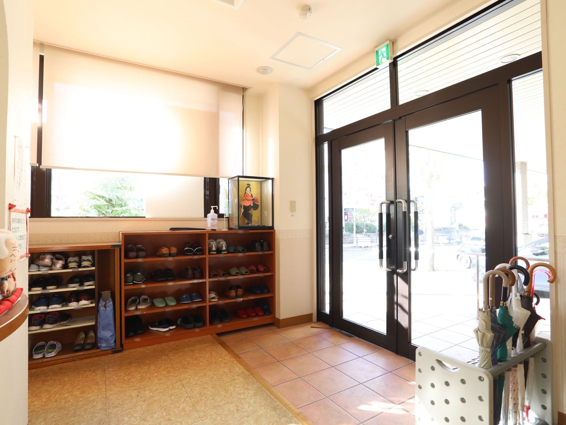 施設の玄関には、茶色い靴箱がたくさん並べられている。入口は、黒枠でガラス張りの扉が取りつけられている。