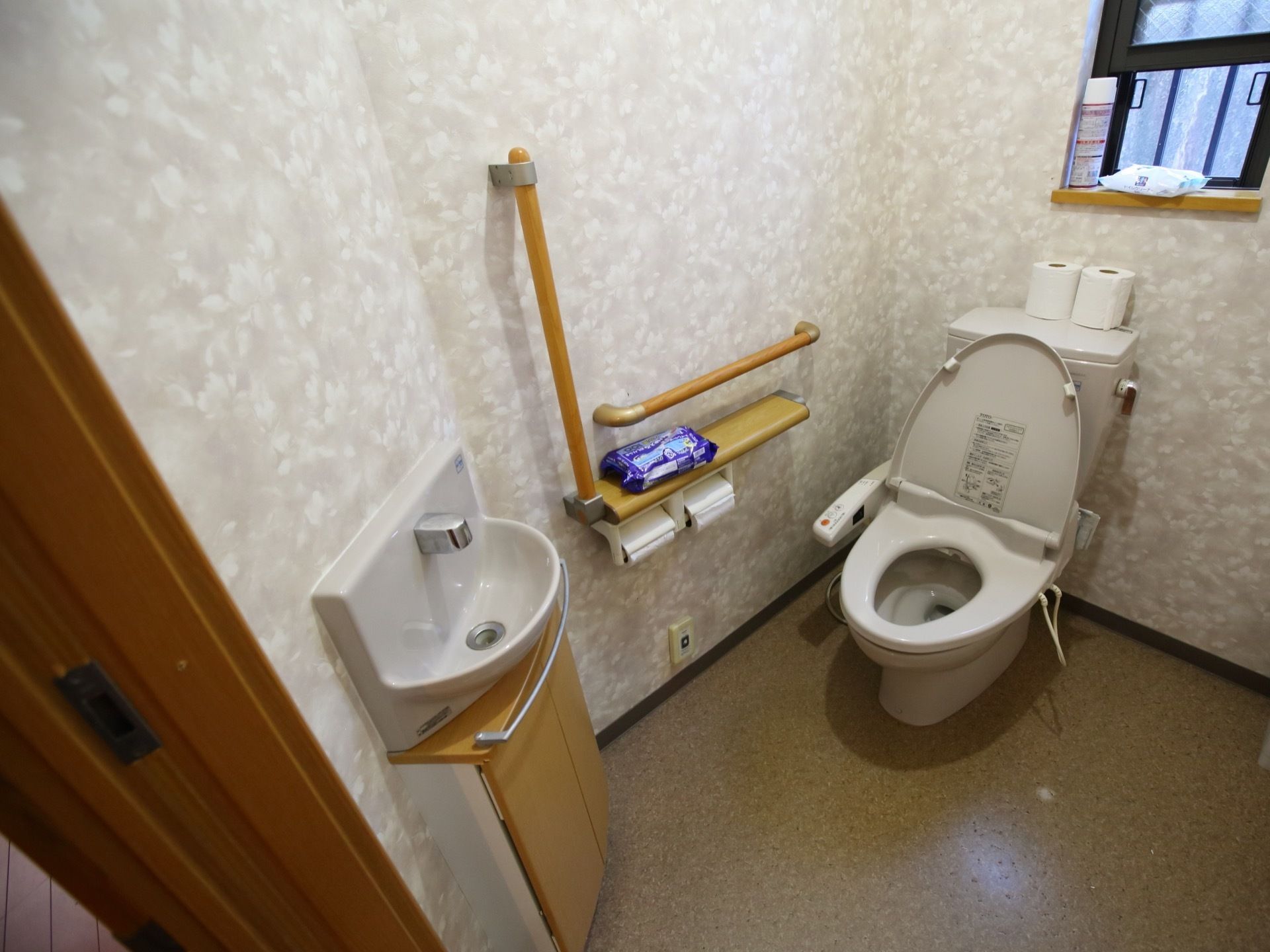 手洗い場と洋式の便器が各１つ備え付けられていて、壁には手すりや緊急呼出しボタンなども設置されている。