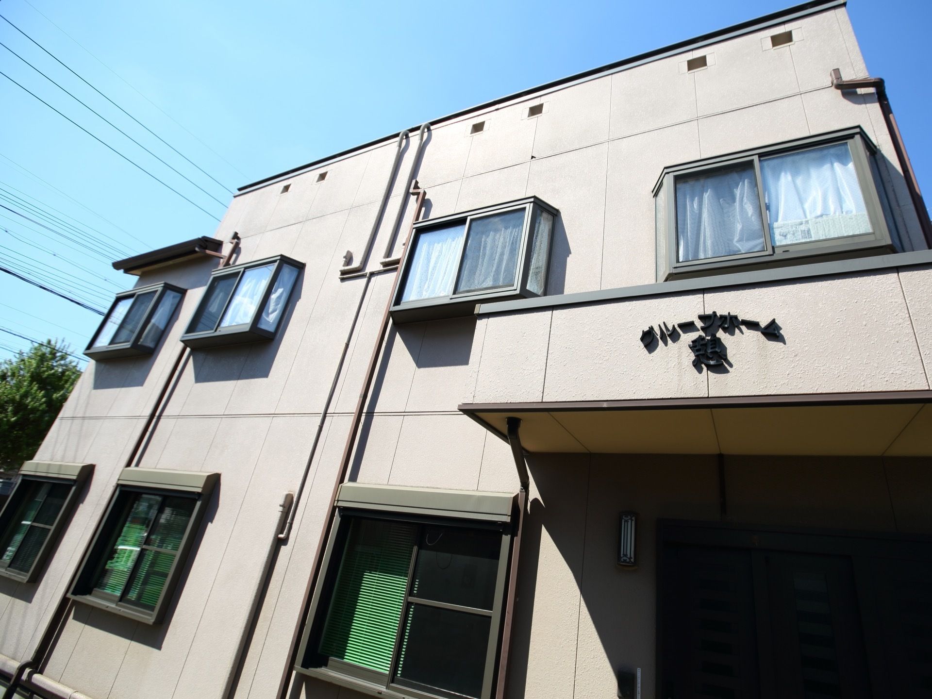 ２階建ての集合住宅のような外観のホーム。２階の４つの窓は出窓になっていて、玄関前のひさしにはホームの名称が書かれている。